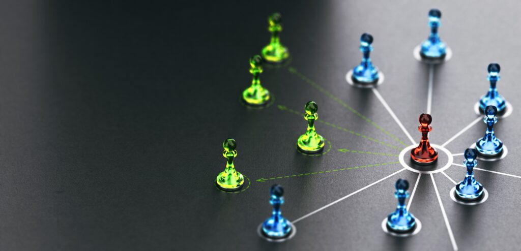 Chess pieces (pawns) in different colours on flat surface linked with a network of lines from a central piece. Image(s) used under license from Shutterstock.com